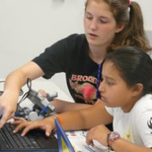 A photo of several girls working in a computer lab on a project.