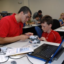 Photo of a student putting together a robot with his mentor