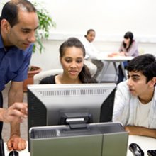 A photo of students working on a computer with their students.